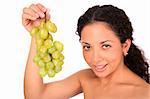 A smiling woman holds a bunch of green grapes, standing on white background.