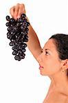 A woman holds a bunch of dark grape in her hand, standing on white backround.