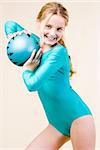 Teenage gymnast with ball on grey background