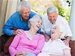 Group of senior friends sitting on garden seat laughing