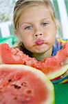 Little blond girl with a piece of watermelon in her hands