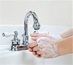 Child washing hands with soap under running water