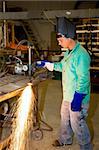 Metal worker in a factory using a track burner to cut a piece of metal.  Authentic and accurate content depiction with all work being performed according to industry code and safety standards.