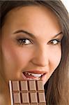 nice brunette with perfect make up eating a block of chocolate looking in camera