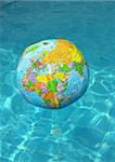 Inflatable ball on a swimming - pool water , globe - designed  and colorfull.  Water is brihg, clean and shalliow.