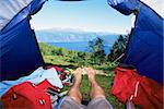 Man lying in tent with a view of lake