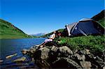 Young woman relaxing on rocks next to lake