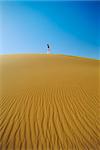 Woman walking across desert sand dune