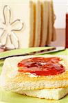 Toast with butter and strawberry jam glass jar in the white plate with soft shadow on square mat background. Shallow depth of field