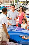 Family discussing new car with salesman on lot