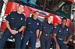 Portrait of firefighters standing by a fire engine