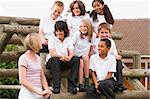 School children sitting on benches outside with their teacher