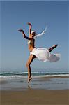 Beautiful young woman jumping on a beach in Greece