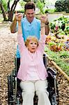 Physical therapist helping a disabled senior woman to regain mobility in her upper limbs.