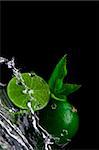 Close up view of fresh limes getting splashed by water