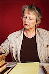 Mature woman with old books takes notes in notepad