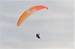 A man with a colorful paraglider flying in the sky