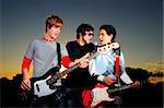 Portrait of three trendy teenagers playing music outdoors