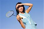 Young woman playing badminton on blue sky background