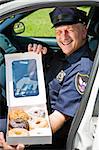 Police officer sitting in his squad car with a box of donuts.