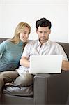 A young couple relaxing at home on the sofa with a laptop computer