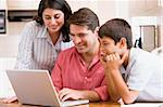 Family in kitchen with laptop smiling