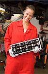 Mechanic holding car part smiling