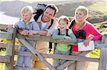 Family on cliffside path leaning on fence and smiling