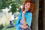 sweet portrait in the park of a red haired girl in autumn dress thinking