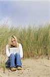 A young woman sits alone on a beach clutching a book full of romantic photographs and memories