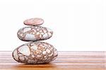 Stack of balanced stones with shadow on wooden background