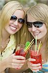 Two beautiful young women enjoying drinks in the summer sunshine