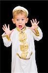 An adorable little boy dressed in Arabian thobe, isolated on black.