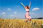 Happy woman wearing sunglasses jumping in golden field