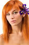 portrait of young redhead woman with purple flower near ear
