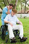 Disabled senior man receiving massage therapy in a lovely outdoor setting.
