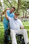 Physical therapist working with disabled senior man outdoors in a natural setting.