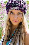 This pretty teen girl is wearing a knitted beanie in a field of tall grass and flowers close-up.