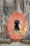 A rusty keyhole on an old wooden door in Spain.