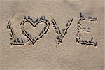 Love sign written on sand with heart shape