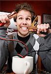 Young man holding jumper cables coming out of coffee mug