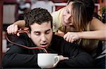 Young woman holding jumper cables coming out of coffee mug to man's head