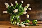 White tulips in glass vase with rustic wood background