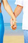 view of a young couple holding hands on the beach