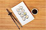 Sushi on the white plate with soy sauce and chopsticks on bamboo mat. Shallow depth of field