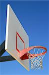 Basketball net and backboard over clear blue sky.