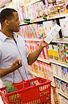 Man shopping in supermarket checking contents of box