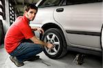 A male chaning a tire on a car