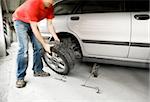A male changing a tire on a car in a garage