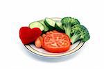 Heart healthy snack concept with a dish of vegetables and plush heart toy isolated on a white background